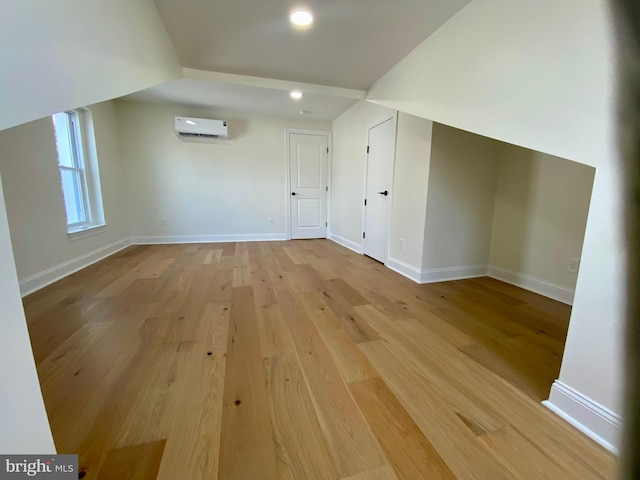 additional living space featuring an AC wall unit and light hardwood / wood-style floors