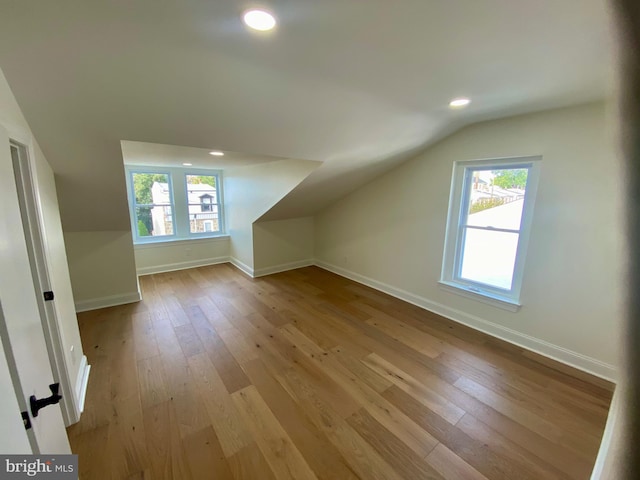 bonus room with light wood-type flooring and lofted ceiling