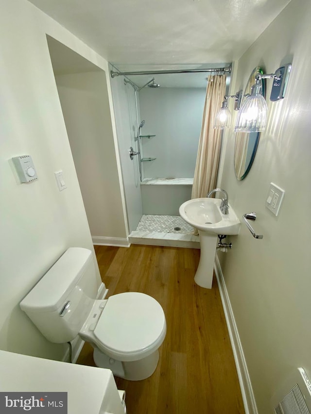 bathroom with toilet, hardwood / wood-style floors, and a shower with curtain