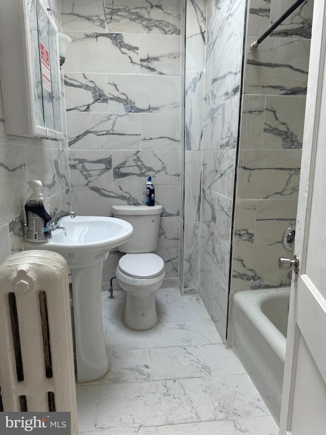 bathroom with tiled shower / bath, tile walls, and toilet