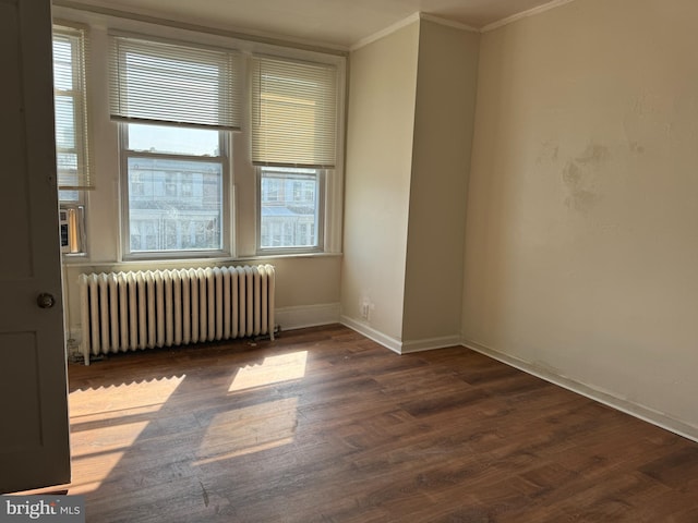 spare room featuring crown molding, dark wood-type flooring, and radiator heating unit