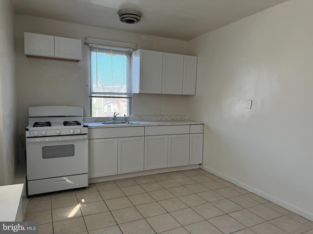 kitchen featuring white cabinetry, light tile patterned floors, white range with gas cooktop, and sink