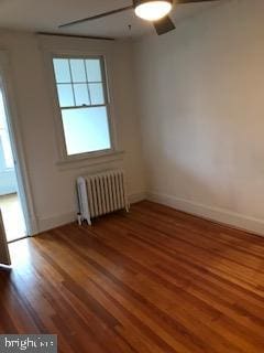 spare room with ceiling fan, radiator heating unit, and dark hardwood / wood-style flooring