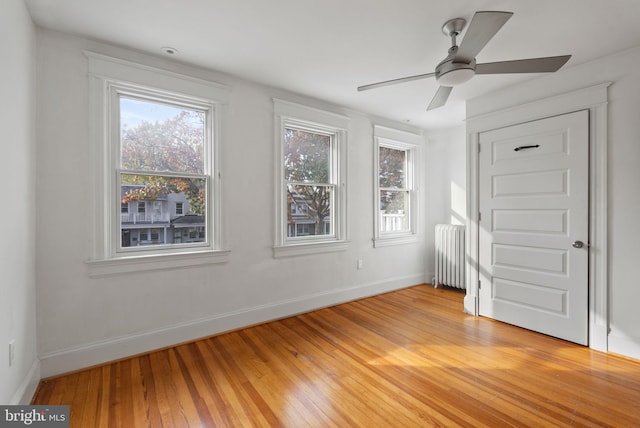 unfurnished bedroom featuring radiator heating unit, ceiling fan, and light hardwood / wood-style flooring