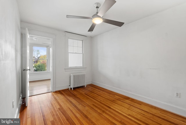 spare room featuring radiator, light wood-type flooring, and ceiling fan