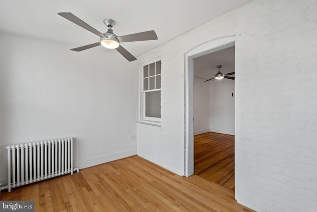 unfurnished bedroom featuring radiator, hardwood / wood-style flooring, and ceiling fan