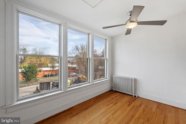 unfurnished room featuring radiator, ceiling fan, and light hardwood / wood-style flooring