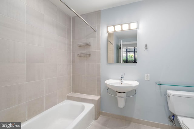 bathroom with tile patterned flooring, tiled shower / bath combo, and toilet