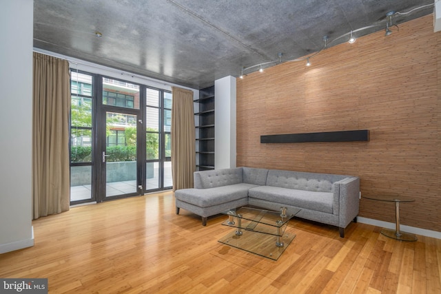 living room with hardwood / wood-style flooring, wooden walls, and track lighting