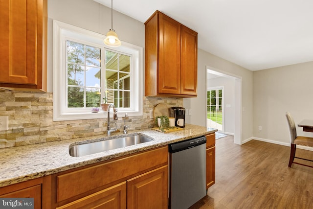 kitchen featuring decorative backsplash, decorative light fixtures, stainless steel dishwasher, hardwood / wood-style floors, and sink