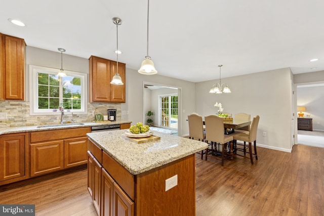 kitchen with pendant lighting, a wealth of natural light, a center island, sink, and hardwood / wood-style floors