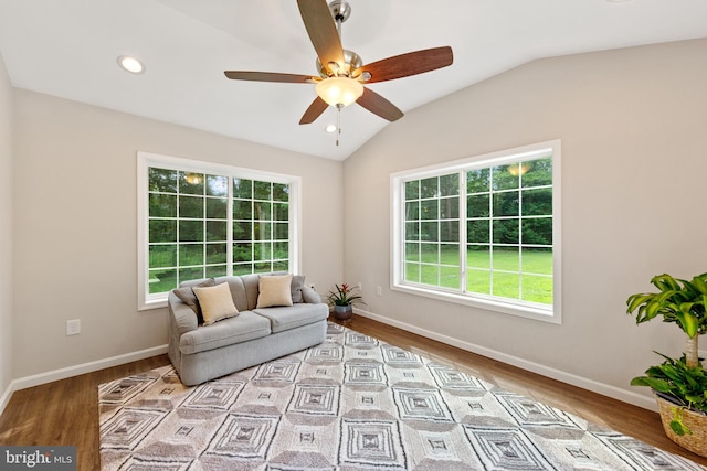 living area featuring ceiling fan, light hardwood / wood-style flooring, vaulted ceiling, and a healthy amount of sunlight