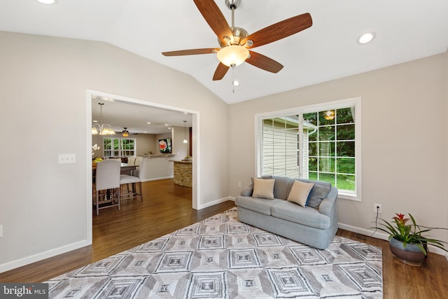 living room with hardwood / wood-style flooring, ceiling fan with notable chandelier, and lofted ceiling