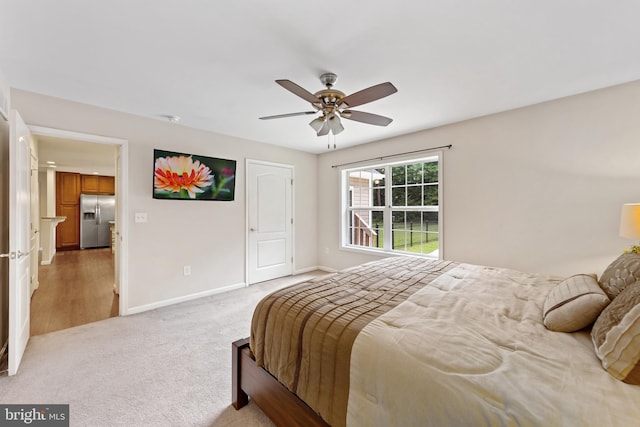 carpeted bedroom with ceiling fan and stainless steel refrigerator with ice dispenser