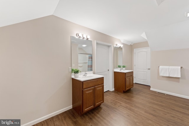 bathroom with lofted ceiling, vanity, and hardwood / wood-style floors