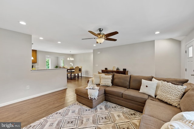 living room featuring ceiling fan with notable chandelier, a wealth of natural light, and wood-type flooring