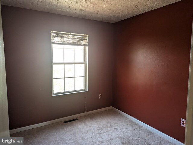 carpeted empty room featuring a textured ceiling