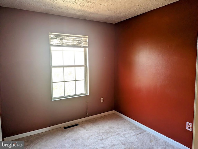 carpeted empty room with a textured ceiling