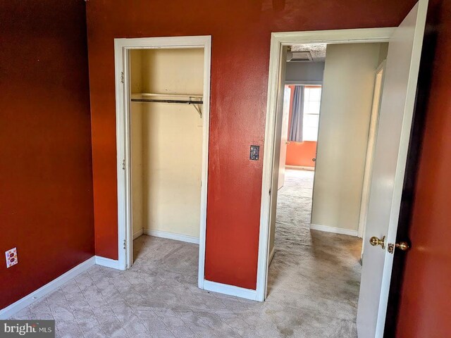 unfurnished bedroom with light carpet and a closet