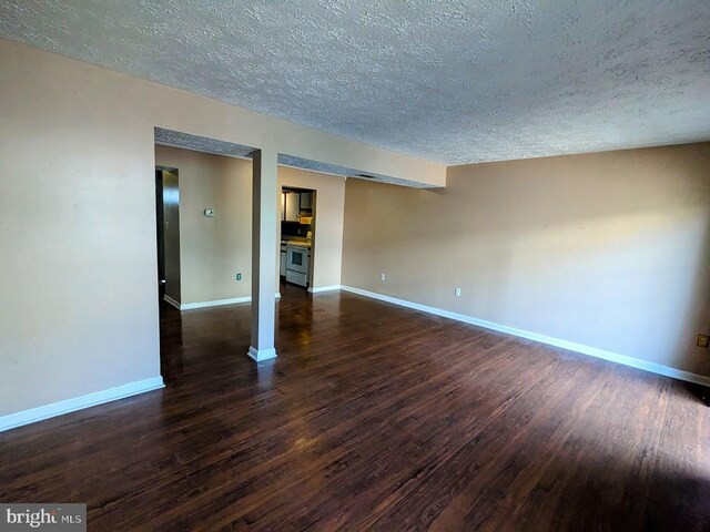 spare room featuring a textured ceiling and dark hardwood / wood-style flooring