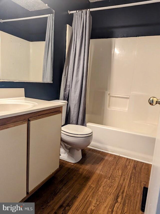 full bathroom featuring shower / tub combo, hardwood / wood-style flooring, vanity, and toilet