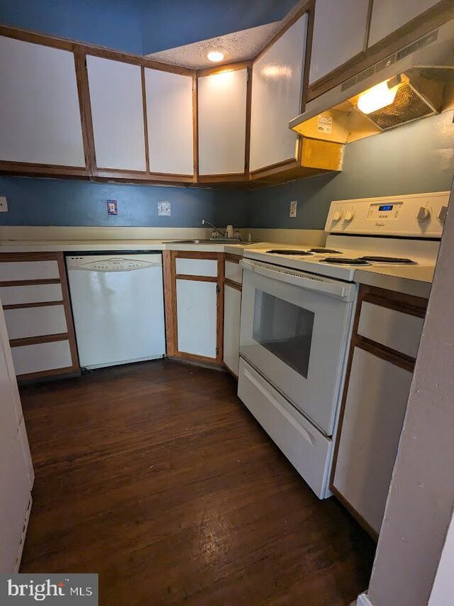 kitchen with white appliances, sink, dark wood-type flooring, and white cabinets