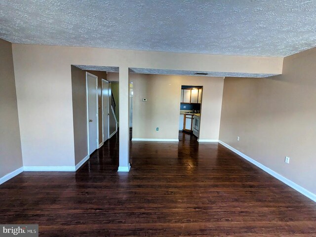 empty room featuring a textured ceiling and dark wood-type flooring