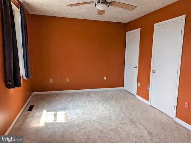 carpeted spare room featuring a textured ceiling and ceiling fan