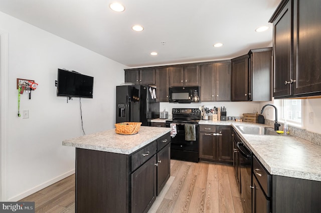 kitchen featuring dark brown cabinetry, sink, a kitchen island, light hardwood / wood-style flooring, and black appliances