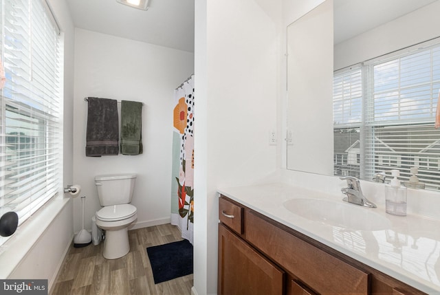 bathroom featuring a healthy amount of sunlight, vanity, toilet, and hardwood / wood-style flooring