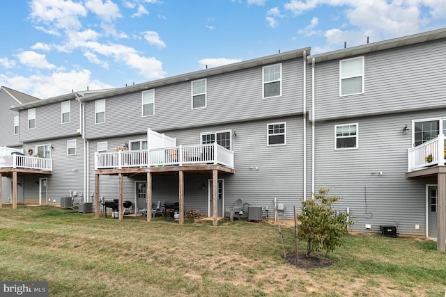 rear view of property with a lawn, a deck, and central air condition unit