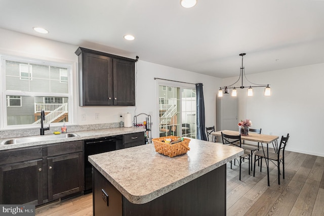 kitchen with sink, decorative light fixtures, light hardwood / wood-style flooring, a center island, and black dishwasher