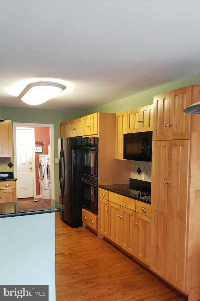 kitchen with black appliances, decorative backsplash, independent washer and dryer, and light hardwood / wood-style floors