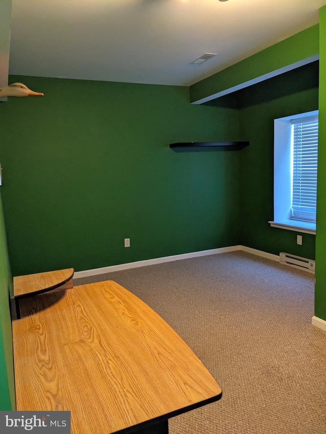 empty room featuring baseboard heating and carpet flooring