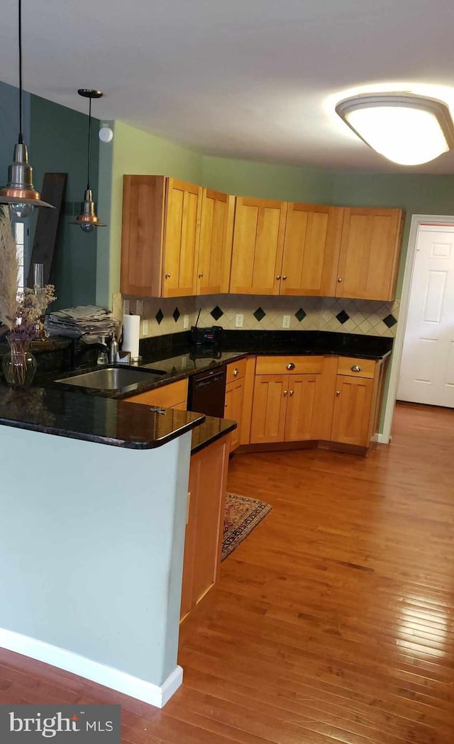 kitchen with kitchen peninsula, wood-type flooring, sink, decorative light fixtures, and tasteful backsplash