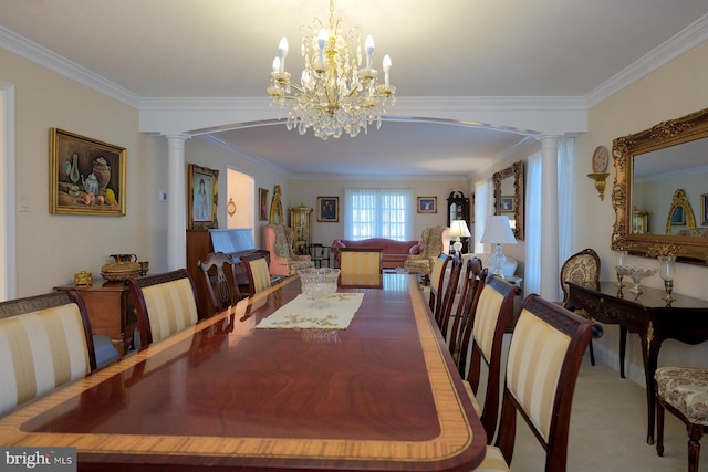 carpeted dining area with ornamental molding, a notable chandelier, and ornate columns