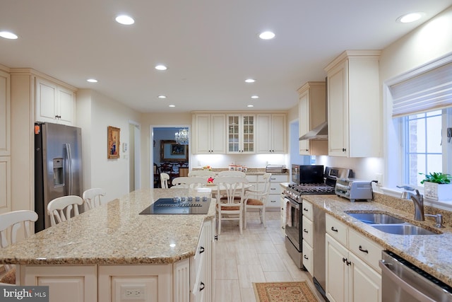 kitchen with light stone countertops, stainless steel appliances, a breakfast bar area, and sink