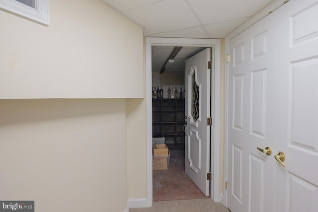 hall with light carpet and a drop ceiling