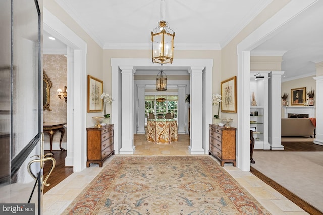 entryway with ornamental molding, light hardwood / wood-style flooring, and decorative columns