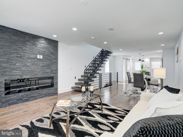 living room with a stone fireplace and hardwood / wood-style flooring