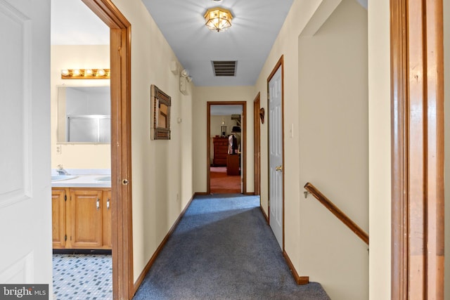 hall featuring dark carpet and sink