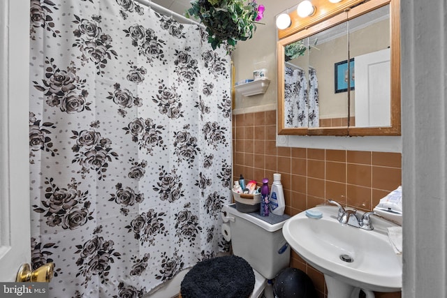 bathroom with tile walls, toilet, walk in shower, and sink