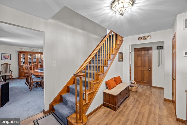 staircase with a notable chandelier and hardwood / wood-style floors