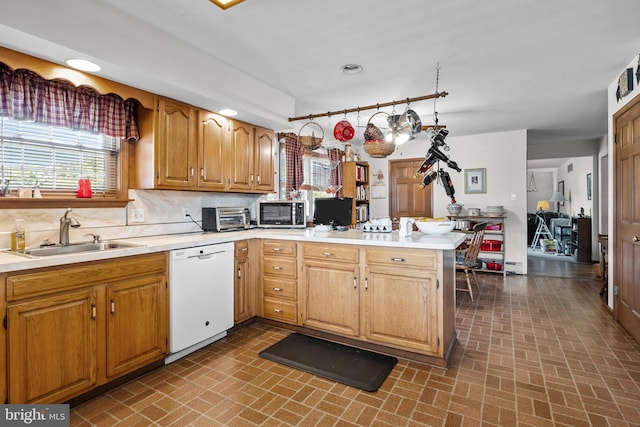 kitchen featuring kitchen peninsula, sink, white dishwasher, and tasteful backsplash