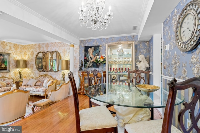 dining space with a notable chandelier, ornamental molding, hardwood / wood-style flooring, and decorative columns