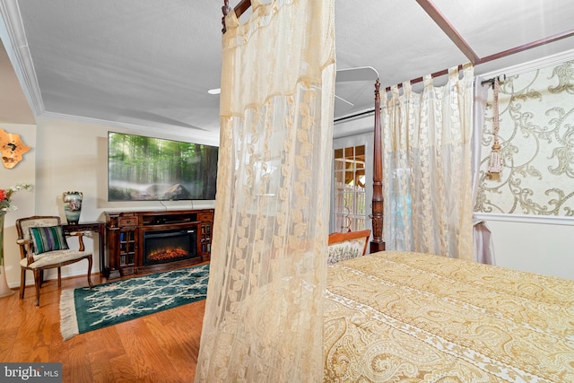 bedroom featuring ornamental molding, wood-type flooring, and a textured ceiling