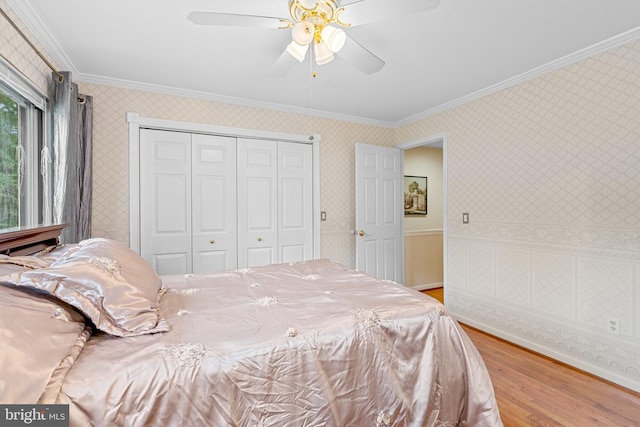 bedroom with ceiling fan, hardwood / wood-style flooring, a closet, and crown molding