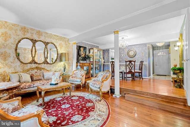 living room with a notable chandelier, crown molding, hardwood / wood-style floors, and ornate columns