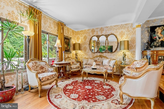 living room with decorative columns, hardwood / wood-style flooring, and crown molding