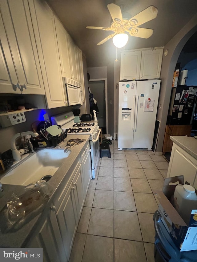 kitchen with light tile patterned flooring, sink, white cabinets, white appliances, and ceiling fan